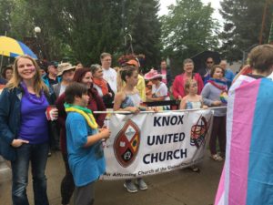 A group of people holding a banner and trans flags. The banner reads "Knox United Church". 