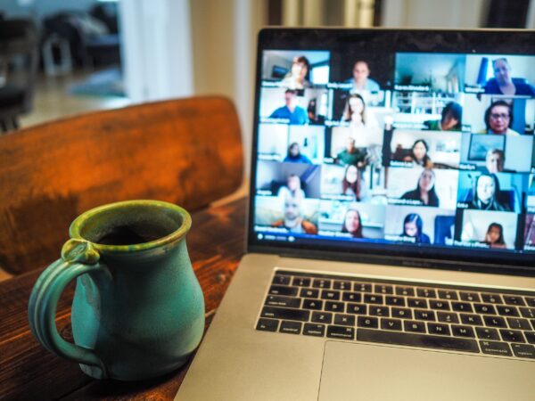 An open laptop with faces in squares, and a blue pottery mug.