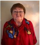 A head and shoulders shot of Gloria Cook, Cree elder. She is wearing a red short with blue designs on it. 