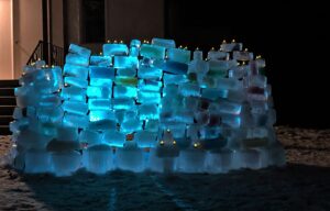 A wall of carefully stacked ice blocks, glowing blue at night. 