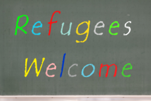 Refugees Welcome in rainbow text on blackboard