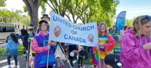 Two teenagers carrying the United Church of Canada Banner amidst multitudes of people