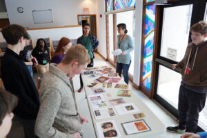 Youth gathered around a table looking at images of Jesus