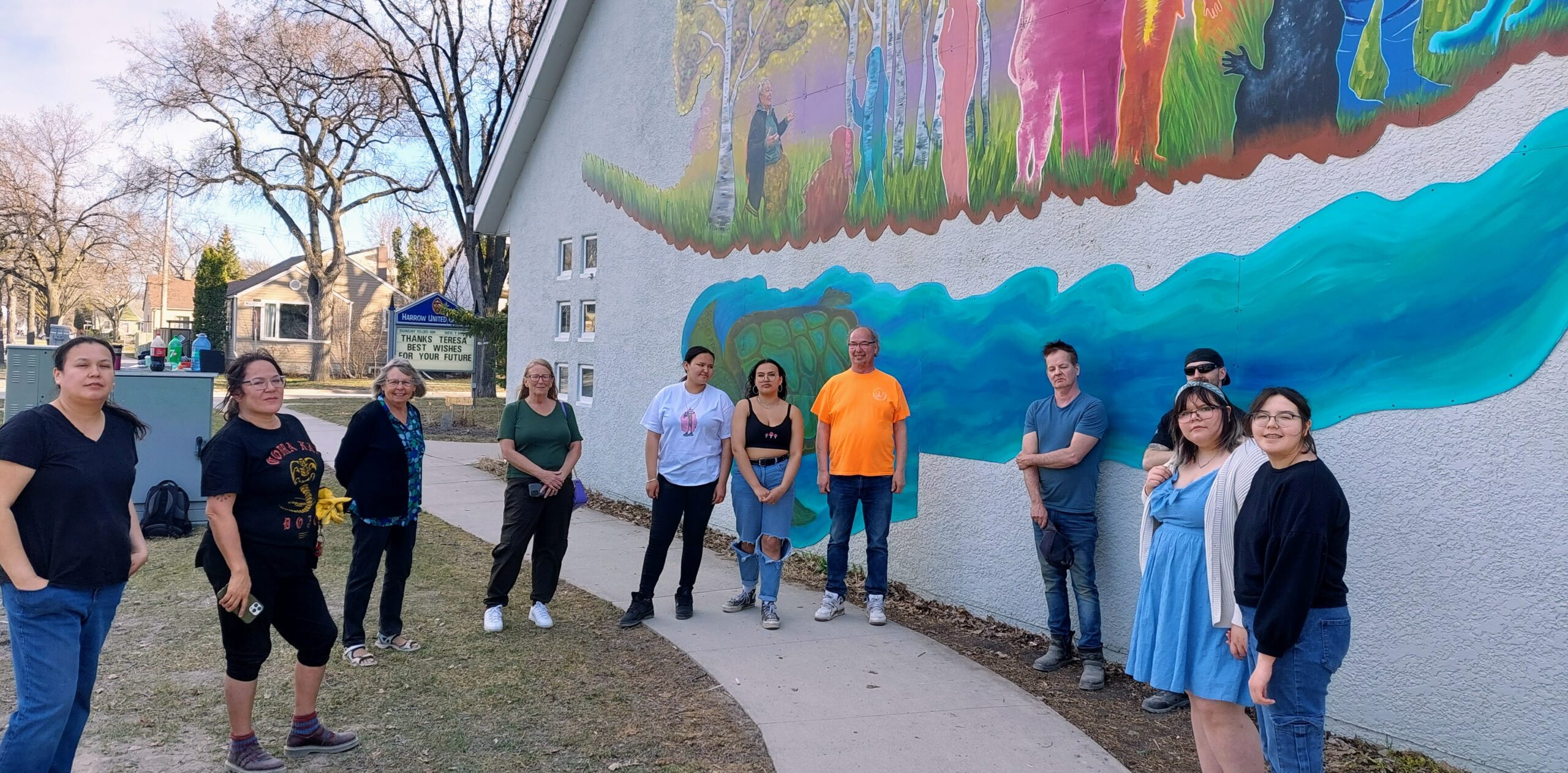 Group of youth and adults in circle in front of completed mural
