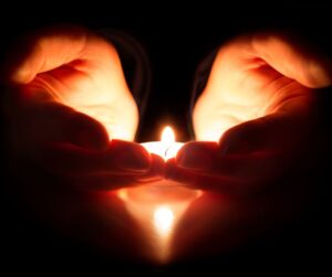 a tealight candle in cupped hands