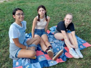 3 youth sitting on a blanket
