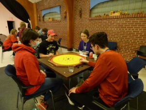 group of youth sitting at a table playing crokinole