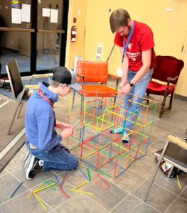 Two youth building with straws