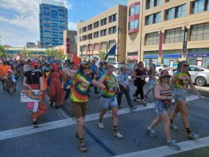 People in Pride attire dancing and walking in parade on Portage Avenue