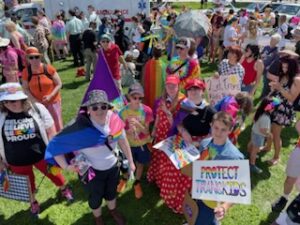 Youth decked out in pride attire and a Protect Trans Kids sign, waiting for Parade to start