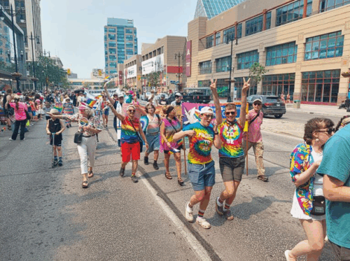 Photo of people in colorful clothes singing and dancing in the parade