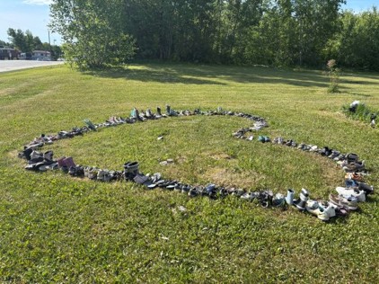 A lawn with trees in the background. In the foreground, a large heart shaped design, made of pairs of shoes.